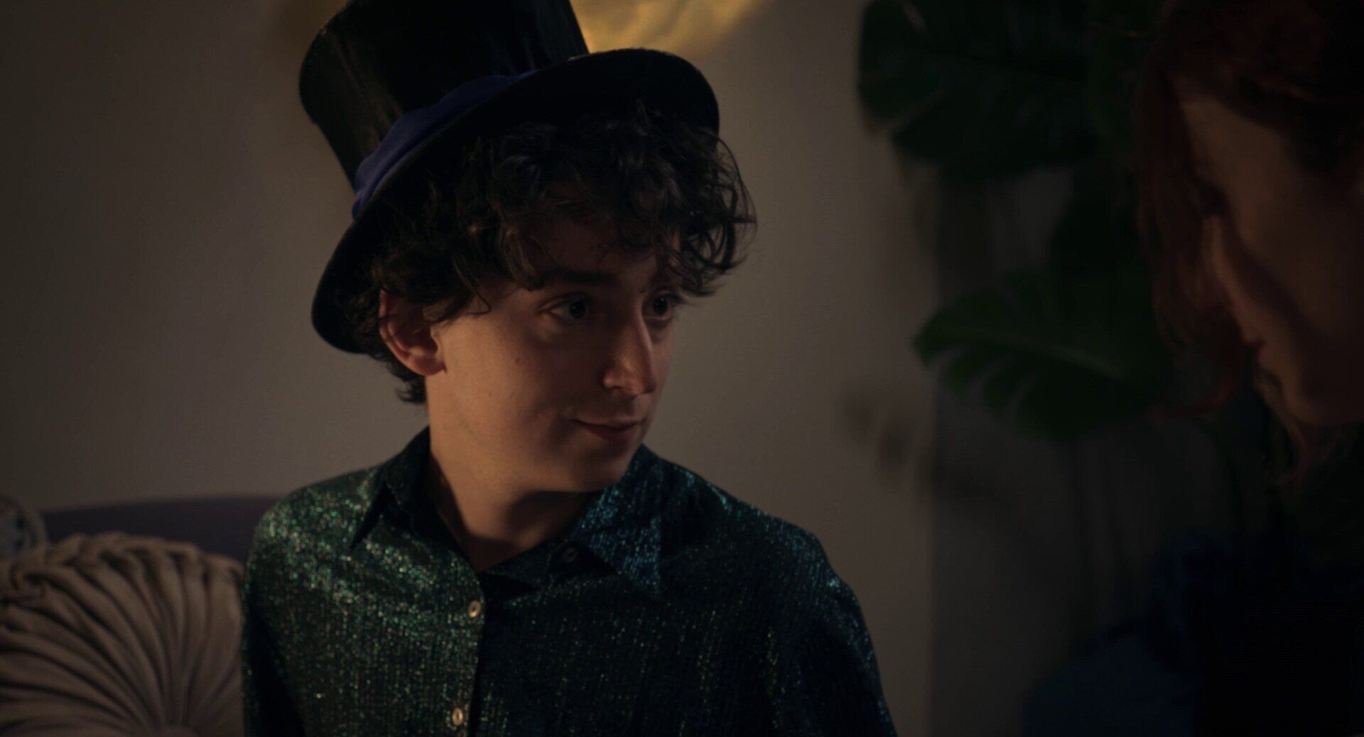 Young performer in a top hat in a warm interior.