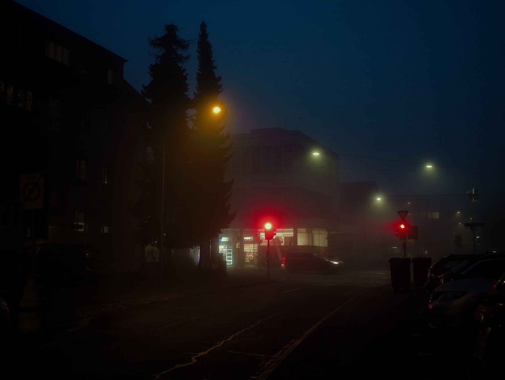 Traffic lights cutting through fog at night.